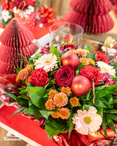 Composition florale avec fleurs rouges et boules de Noël.
